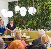People participating in a mixology workshop in a room with a green plant wall and modern lighting.