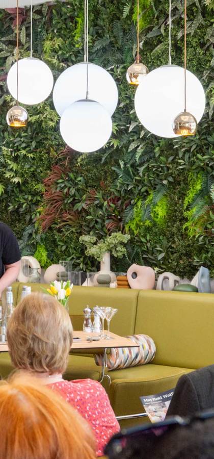 People participating in a mixology workshop in a room with a green plant wall and modern lighting.