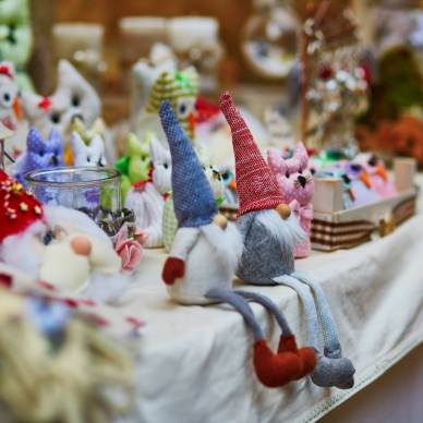 A table displays various fabric gnomes and animal figurines at a craft fair.
