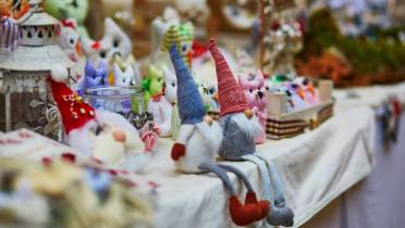A table displays various fabric gnomes and animal figurines at a craft fair.